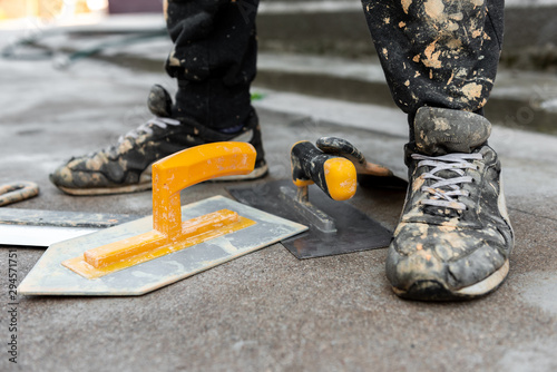 Construction trowel comb and dirty feet of builder.