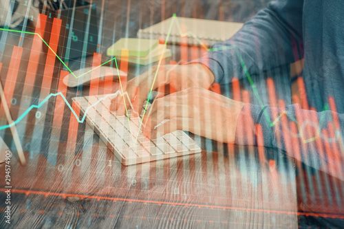 Stock graph with businessman typing on computer in office on background. Concept of analysis. Double exposure.