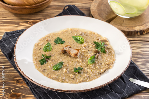 Risotto with porcini mushroom with basil and parsley serving size on wooden table