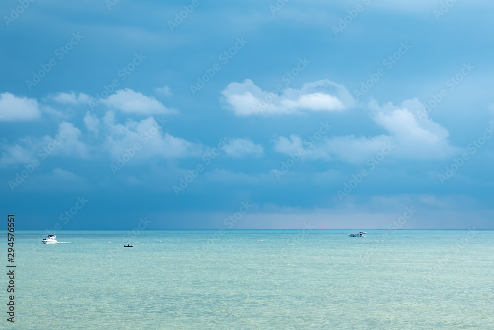 Blue sea and several boats on a cloudy day