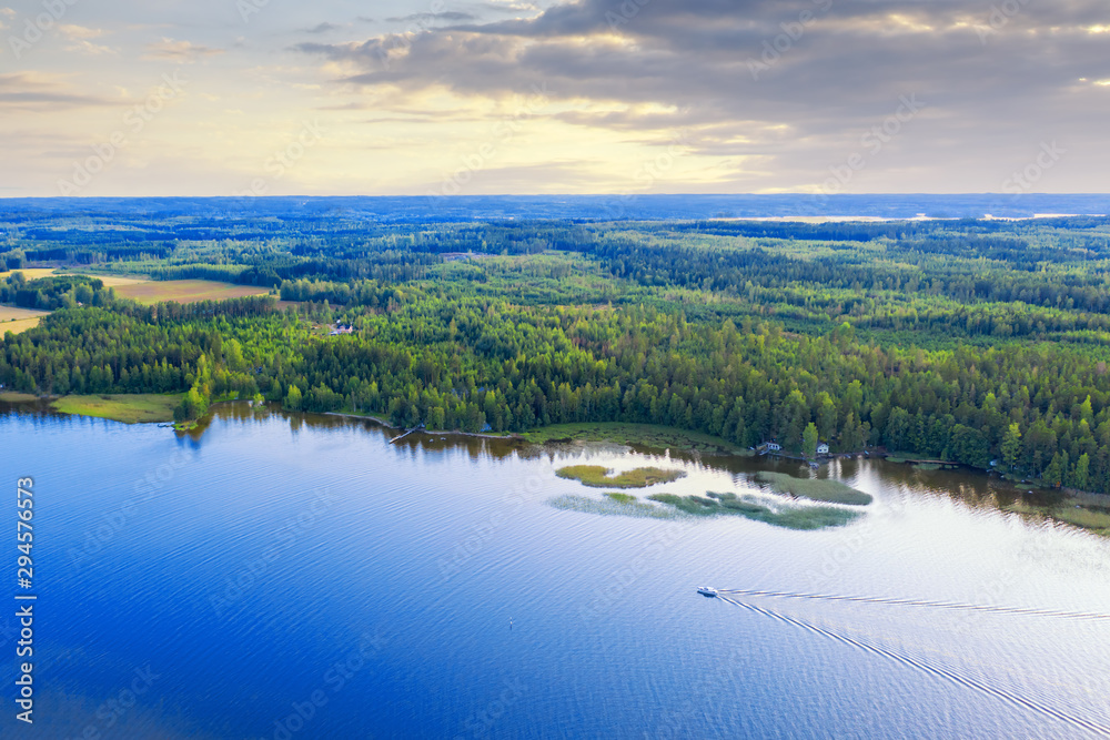 Aerial view of Pulkkilanharju Ridge, Paijanne National Park, southern part of Lake Paijanne. Landscape with drone. Blue lakes, boat and green forests from above on a sunset in Finland.