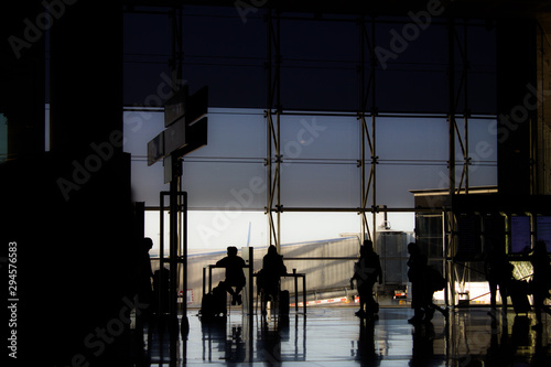 sitting and walking peorple on a airport. Backlight at Windows