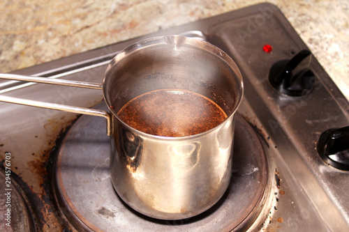 Coffee brewing in a coffee maker on a stained dirty electric stove photo