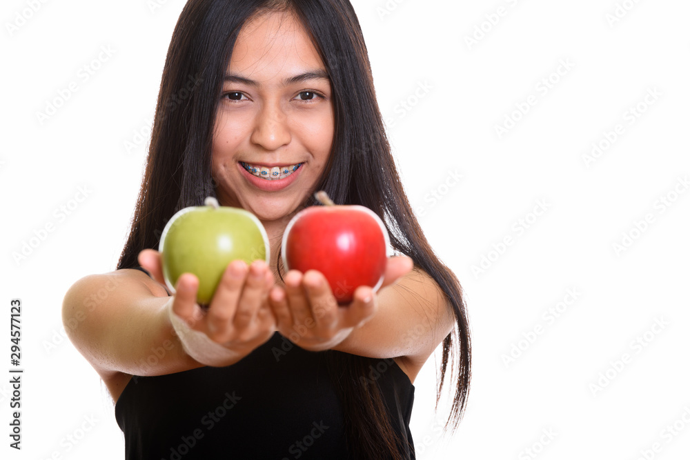 Young happy Asian teenage girl smiling while giving green and re Young happy Asian teenage girl smiling while giving green and re