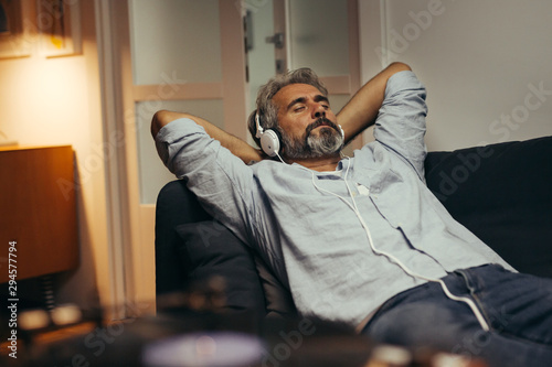 mid aged man relaxing home and listening music photo