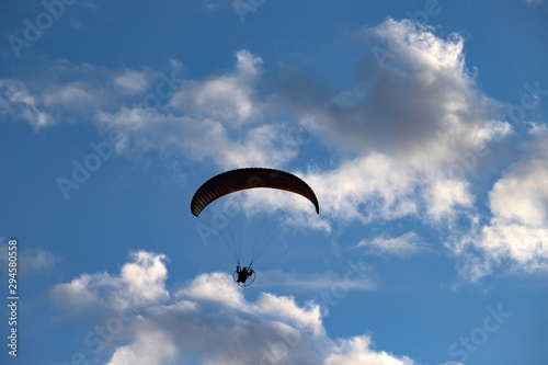 Paraglider silhouette over blue sky.
