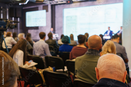 Conference participants, events, presentations, listen to the speaker sitting in chairs.