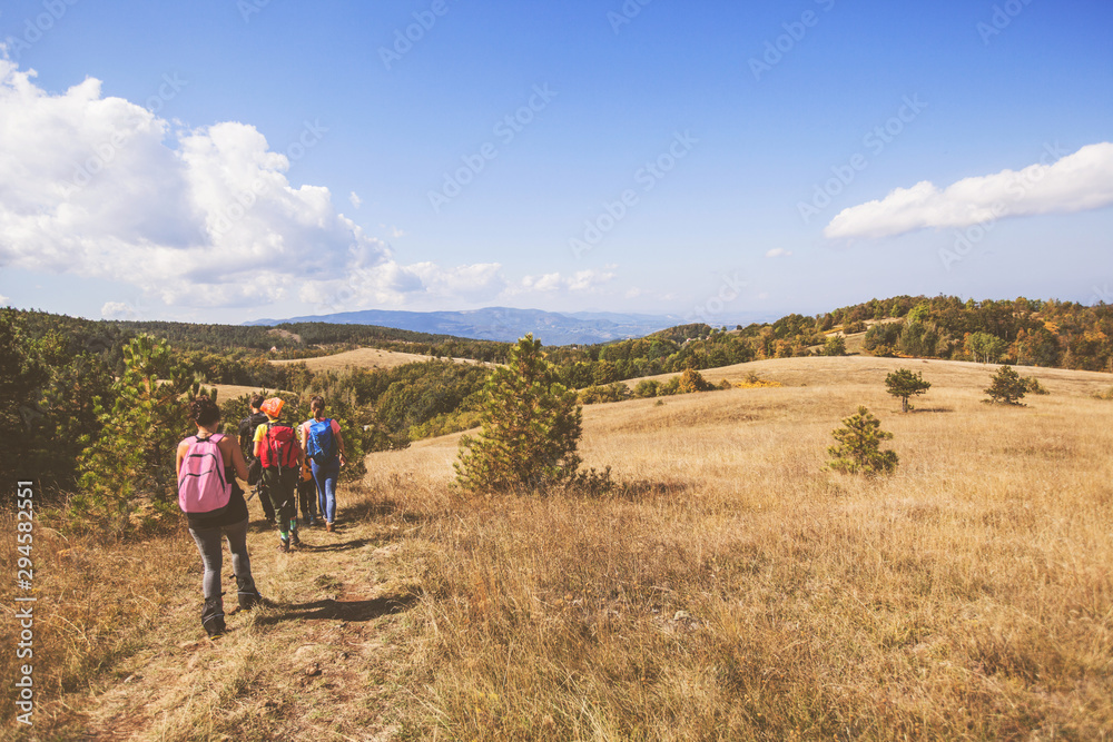 Rear view of unrecognizable people with backpack hiking in the nature