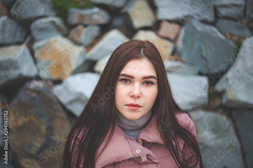 Portrait of a young tired pretty pregnant girl in a pink warm down jacket. Late autumn, the cold is coming. toned photo.