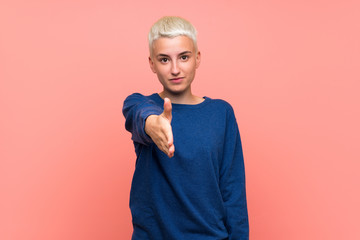 Teenager girl with white short hair over pink wall shaking hands for closing a good deal
