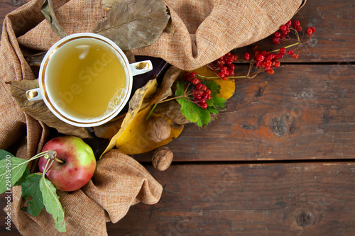 Autumn still life with cup of tea, plaid and leaves on wooden background