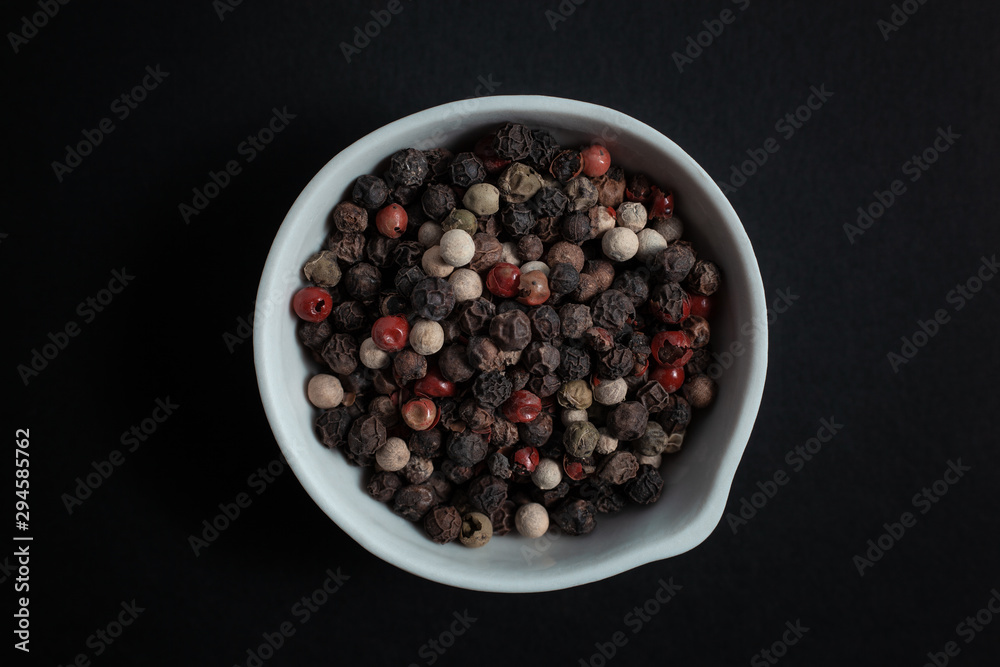Peppercorn pepper spice in a white ceramic bowl isolated on black background Peppercorn pepper spice in a white ceramic bowl isolated on black background