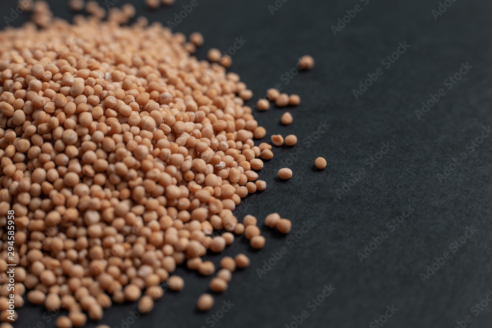 Spice mustard seeds scattered on a black background