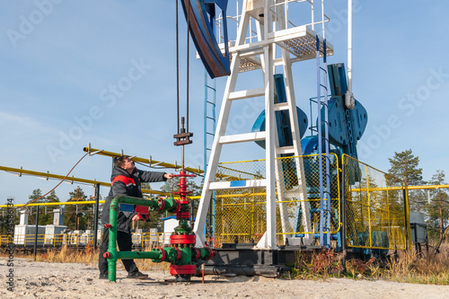 A man near the oil pump. Oil, gas industry. A man controls the process of the oil pump, the overall plan.