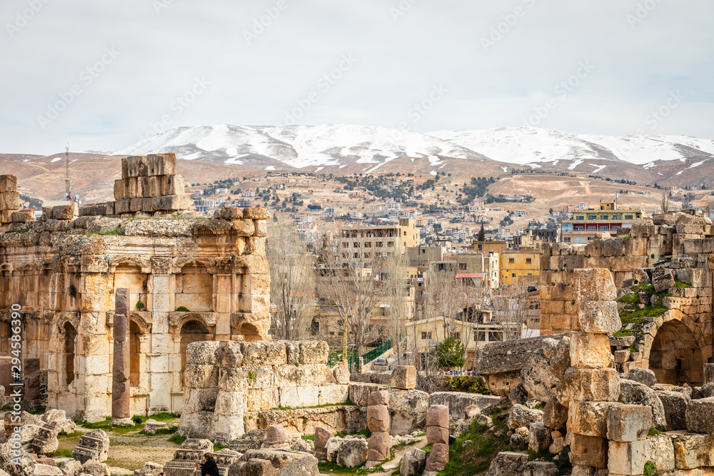 Ancient ruins of Grand Court of Jupiter temple, with modern lebanese houses in the background, Beqaa Valley, Baalbeck, Lebanon