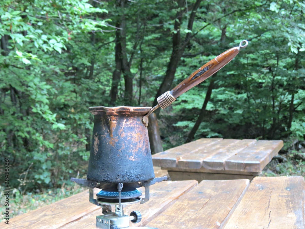 Preparing breakfast or tourist morning coffee in portable camp gas stove or skillet. Camping, hiking, adventure photo