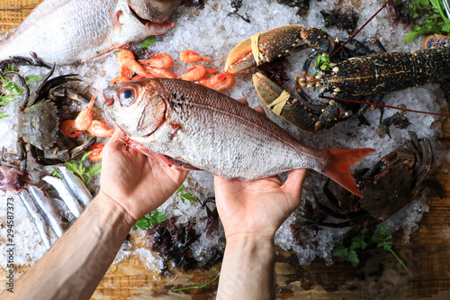 Top view of chef's hands with fish on a background of ice and sea food