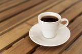 Tasty cup of black coffee on wooden table
