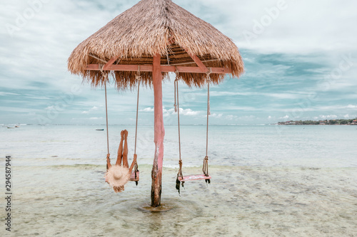 Girl on beach swing on Bali island