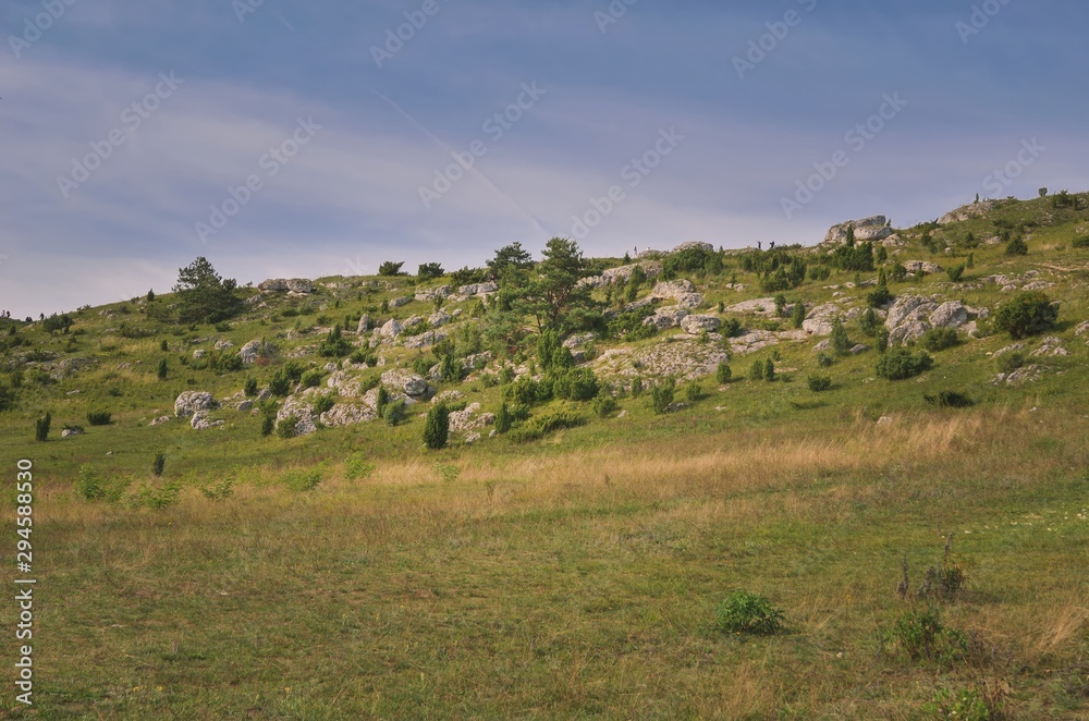 Obraz premium Sunny summer landscape. Beautiful rocks between the green hills.