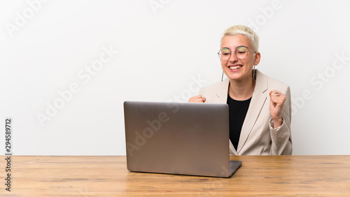 Teenager girl with short hair with a laptop celebrating a victory in winner position © luismolinero