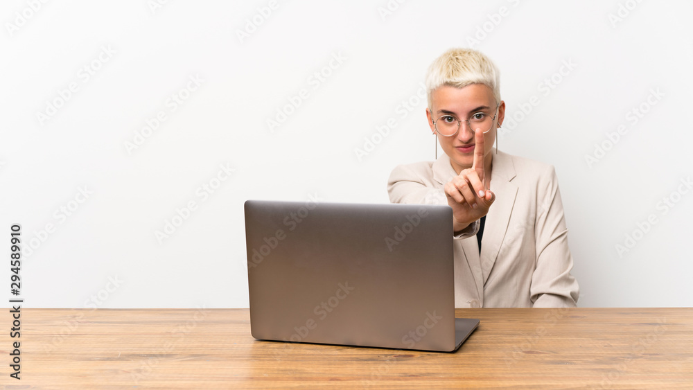 Teenager girl with short hair with a laptop showing and lifting a finger Teenager girl with short hair with a laptop showing and lifting a finger