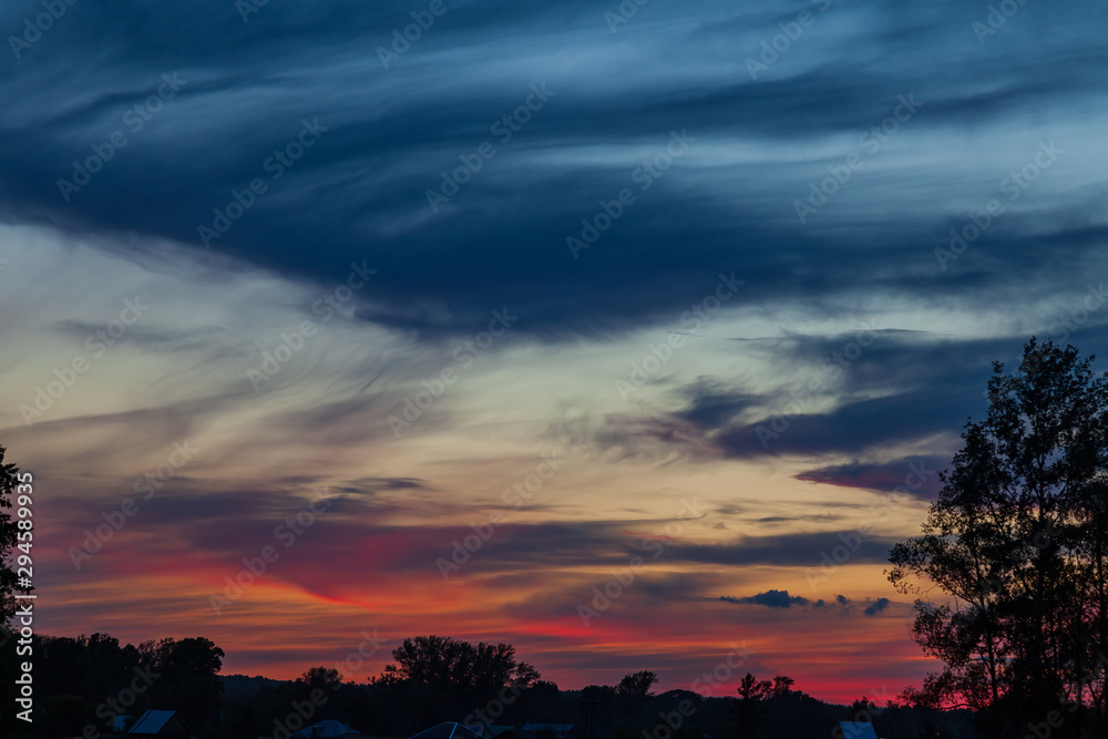 Picturesque landscape overlooking a red-orange sky with clouds and clouds at sunset at blue hour before the rain. Wallpaper and background with the concept of freshness and naturalness.