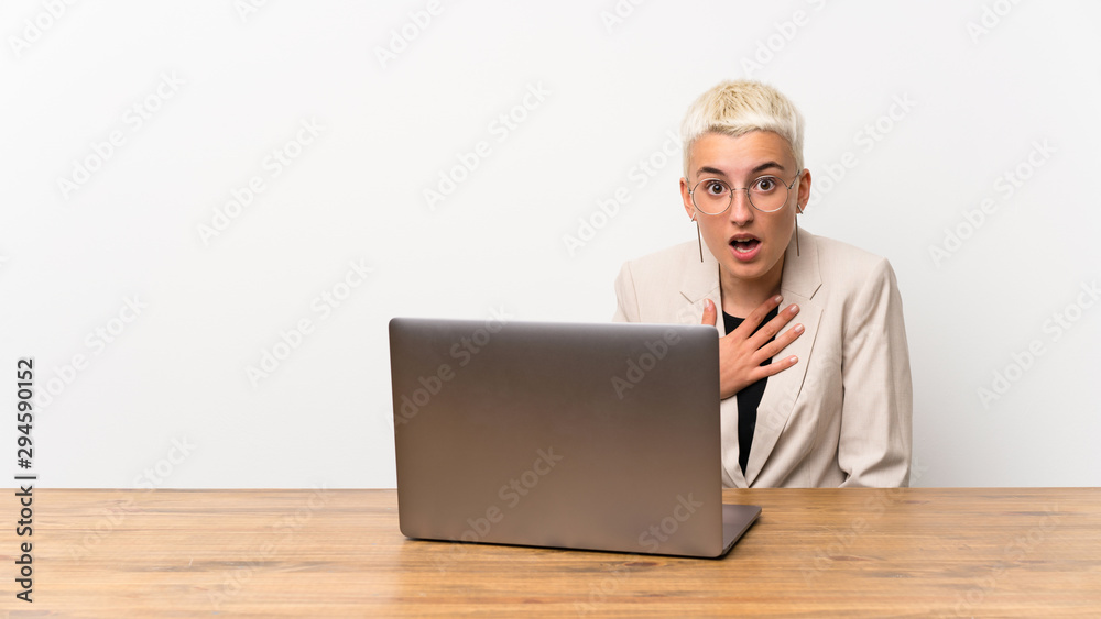 Teenager girl with short hair with a laptop surprised and shocked while looking right Teenager girl with short hair with a laptop surprised and shocked while looking right