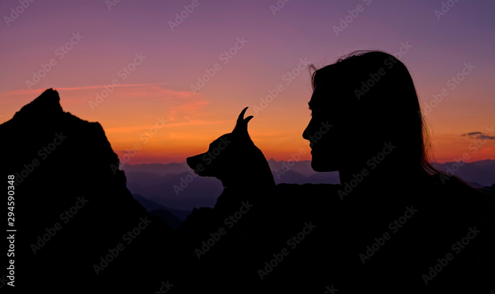 SILHOUETTE: Hiker and her puppy watch the sunrise from a mountaintop in Slovenia