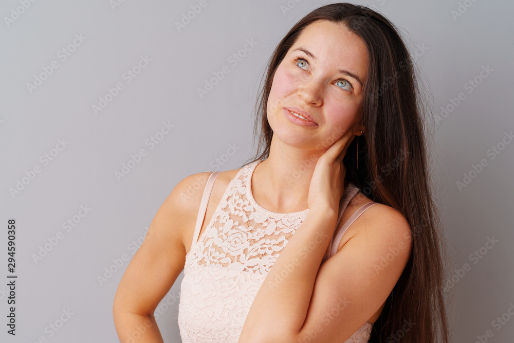Image of thinking young woman standing over a gray background. Image of thinking young woman standing over a gray background.