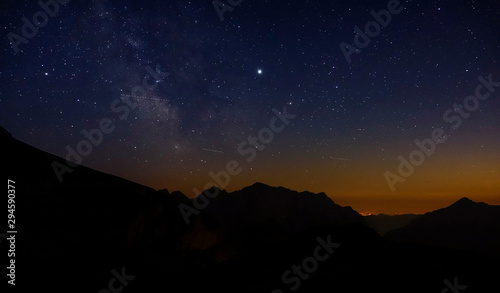 Shooting stars fly across the evening sky spanning above the serene Julian Alps.