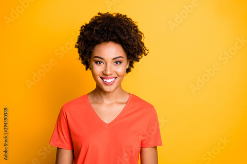 Photo of attractive cheerful cute funky girlftiend smiling toothily wearing orange t-shirt isolated over yellow vivid color background