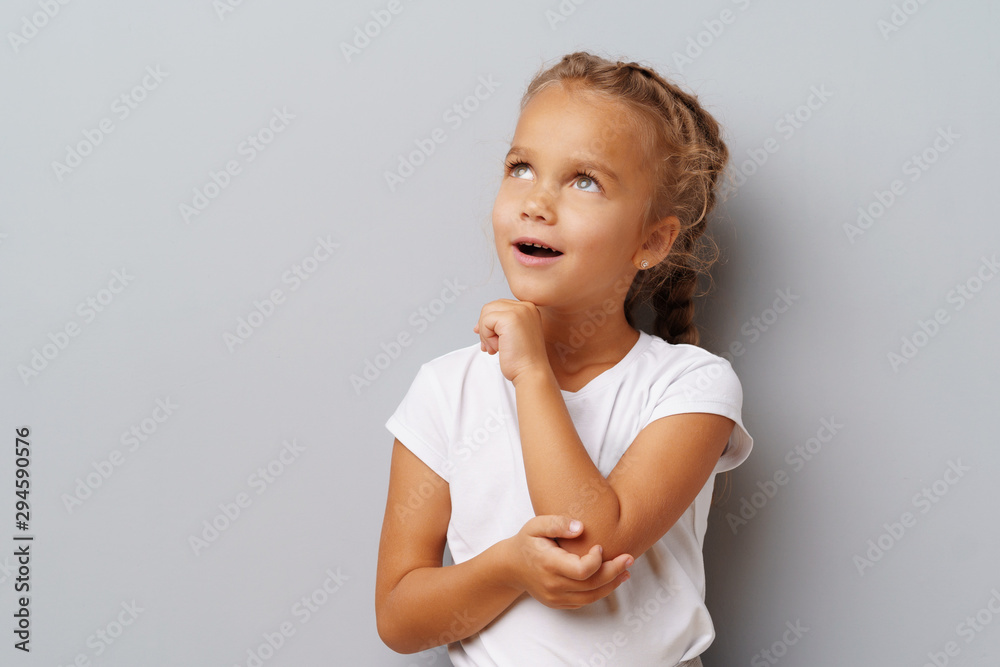 Image of thinking little girl standing over a gray background Image of thinking little girl standing over a gray background