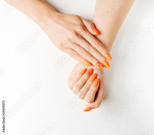 Female hands with beautiful manicure of orange color.