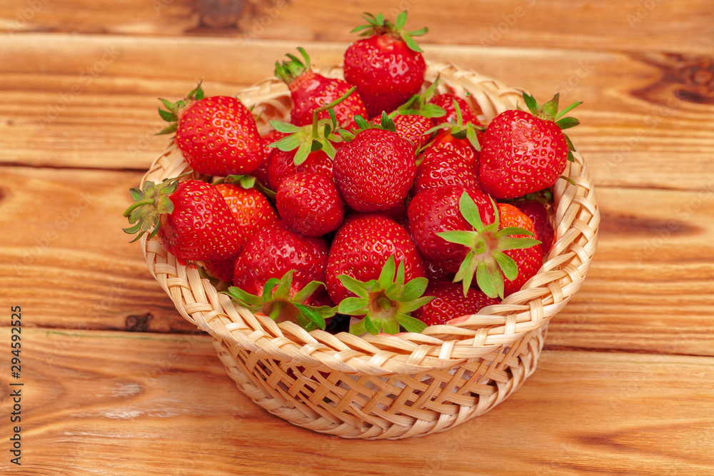 Basket of strawberry harvest on wooden table close up