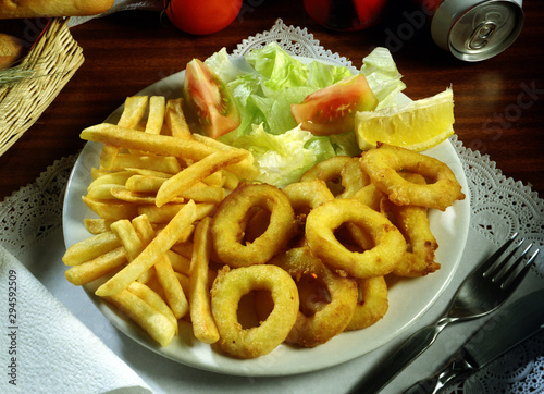 Canvastavla Plato de calamares a la romana con patatas fritas y ensalada.