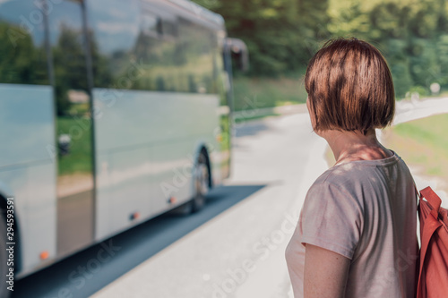 Female hiker looking at bus passing by her