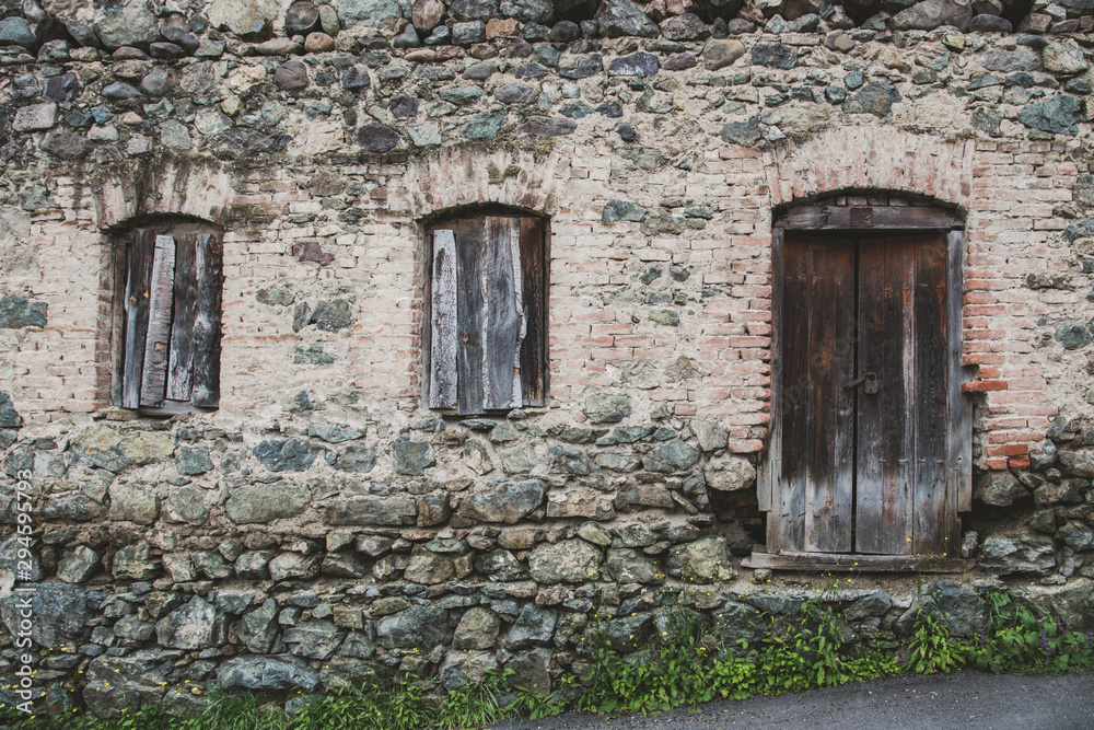 Old wooden door in stone wall - abandoned house in Dilijan, Armenia