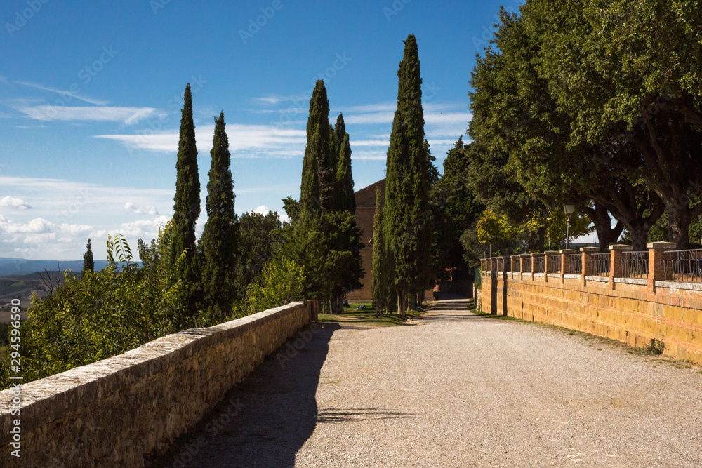 Cobblestone path of the Pienza promenade. On the left a panoramic view of the Tuscan countryside.