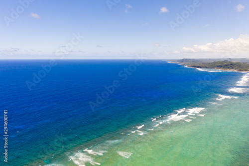 Seascape, coast of the island of Siargao, Philippines. Blue sea with waves and sky with big clouds, top view.