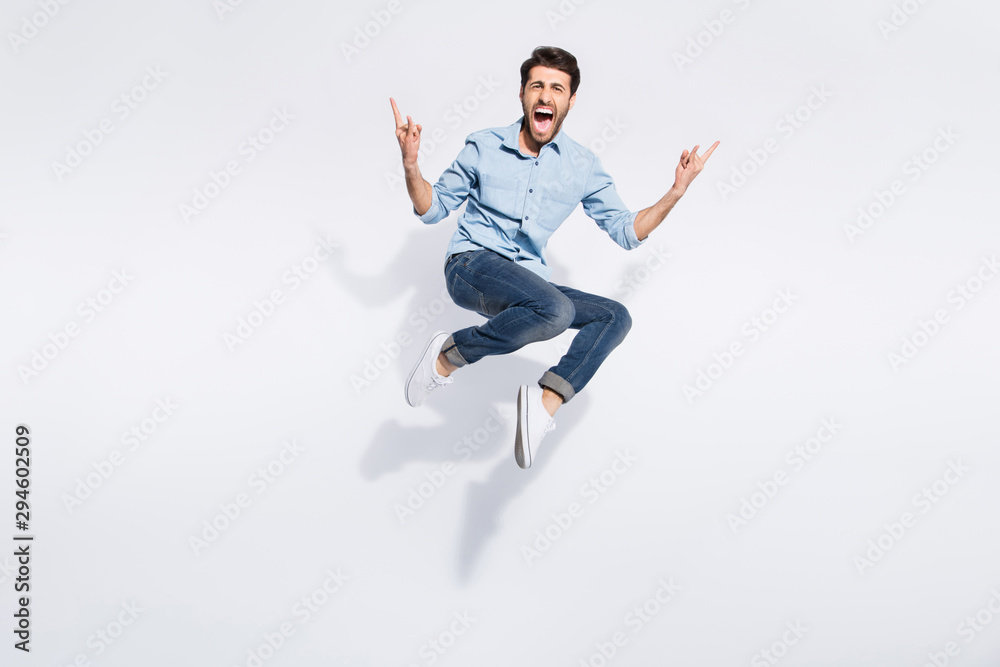 Full length photo of wild indian guy jumping high at hard rock concert making finger horns symbol wear casual denim clothes isolated white color background