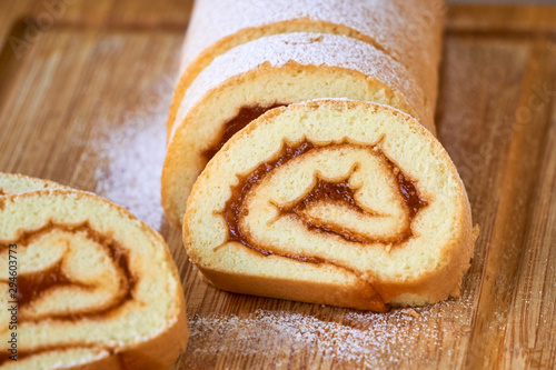 Biscuit roll with apricot jam on a wooden board photo