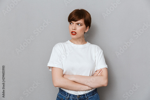 Image of resentful brunette woman frowning and standing with arms crossed