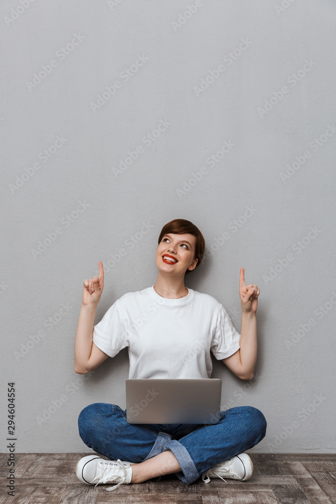 Image of woman pointing finger upward while sitting with laptop