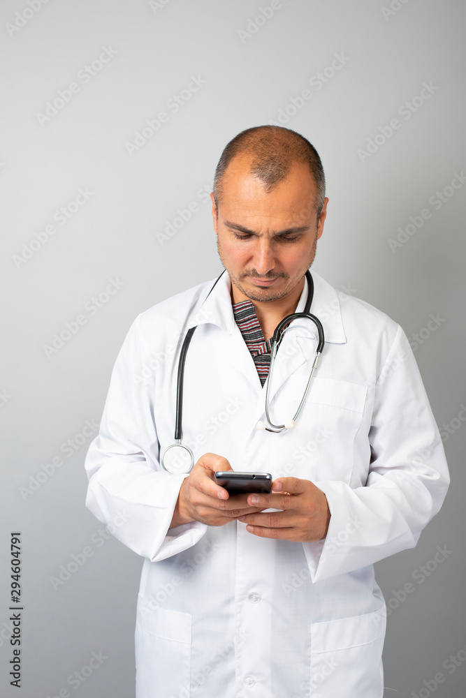 Male doctor is typing a text message on a mobile phone Male doctor is typing a text message on a mobile phone
