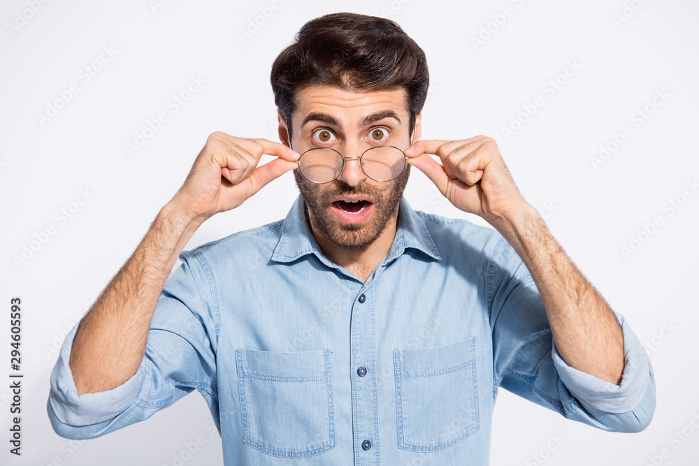Closeup photo of handsome indian guy not believe eyes staring on awful bad news on television wear specs casual denim shirt isolated white color background Closeup photo of handsome indian guy not believe eyes staring on awful bad news on television wear specs casual denim shirt isolated white color background