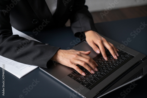 Top view of young woman hands typing on laptop at office table or at home. Documents on the desk. Concept of business and education
