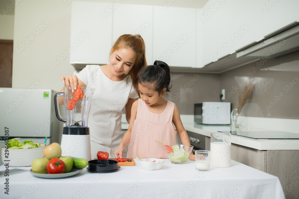 Young Asian mother and daughter making freshly squeezed tomato smoothies, daughter is very happy Young Asian mother and daughter making freshly squeezed tomato smoothies, daughter is very happy