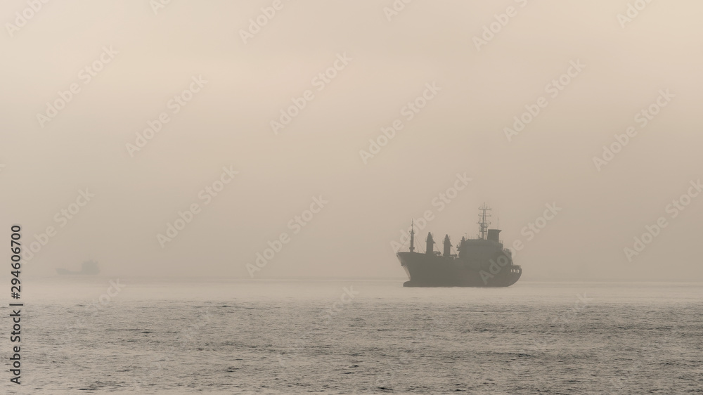 Cargo ship sailing on ocean in the morning with sky and sea background, Silhouette ship sailing in foggy morning.