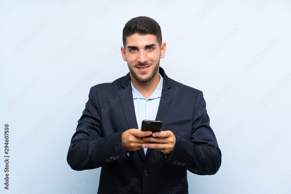 Handsome man over isolated blue background sending a message with the mobile Handsome man over isolated blue background sending a message with the mobile